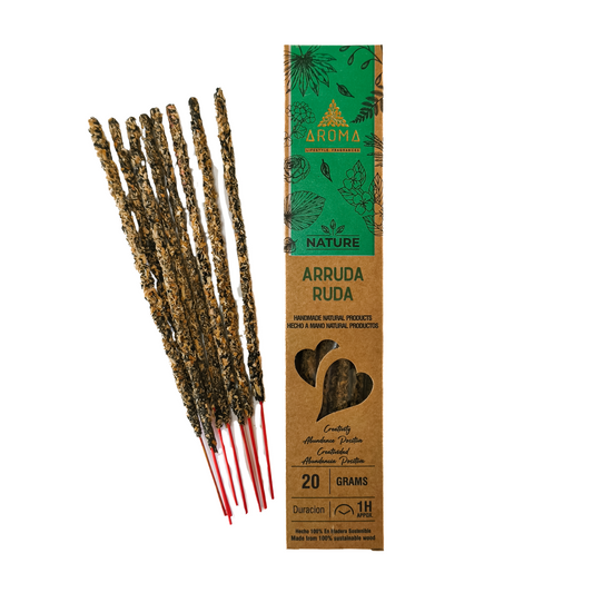 Incienso artesanal y orgánico, con el texto "Incienso de Ruda" visible en el empaque. El humo se eleva suavemente.