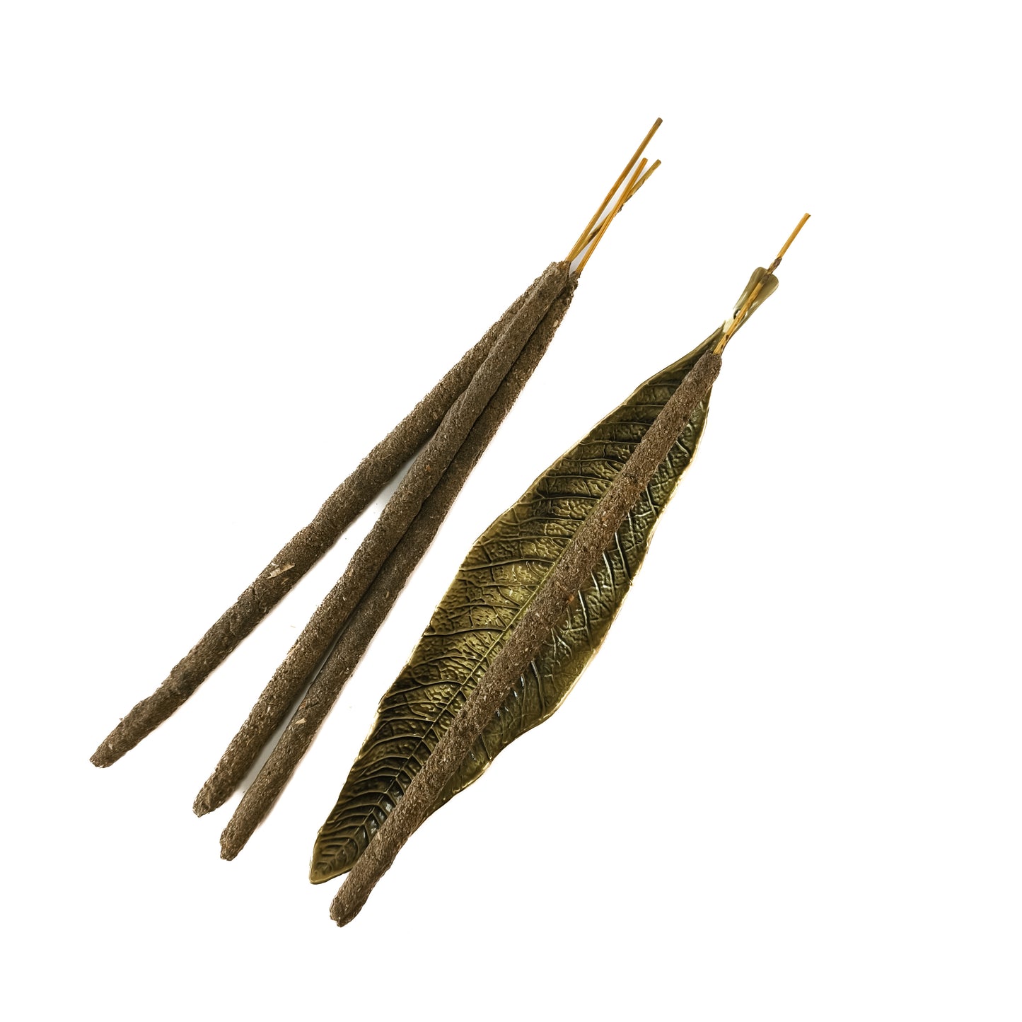 Un porta incienso de metal pequeño con forma de hoja en color bronce. La varilla de incienso está encendida sobre la hoja.